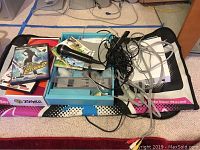 Photo showing Nintendo Wii console, microphone, several cables, balance board and a PlayStation 2 game along with a Zumba fitness mat