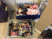 Clear photo of two storage bins; one bin contains assorted Barbie dolls and clothes, the other is a clear plastic bin with a colorful bag containing My Little Pony toys and other accessories.