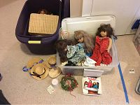 Bins and basket lid containing dolls, wreath and hats