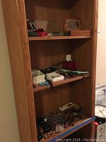 Wooden shelving unit displaying assorted jewelry pieces and watches arranged on shelves, including bracelets and beaded necklaces