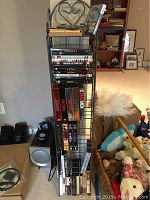 Black wire shelving unit filled with DVD movies and series in cases and boxed collections, placed against a wall