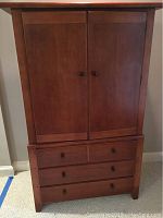 Front view of the Thomasville armoire showing two upper doors and three lower drawers with matching round wooden knobs.