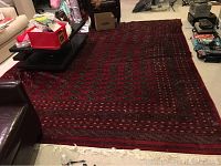 Full view of red Bokhara rug laid on floor showing repeating octagonal gul pattern and multi-border design