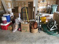 Wide shot showing various items including red and blue coolers, hand truck, garden hoses, fireplace tools, charcoal bags, baskets and boxes.