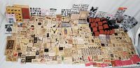 Wide view of large collection of craft stamps including wood mounted, clear rubber, roller stamps arranged on table with multiple themes and images
