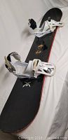 Full view of the black Burton snowboard with white bindings mounted, showing length and condition.