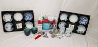 Wide photo showing all items in the lot on display: boxed bowls, teapots, cups, and tea accessories centrally arranged.