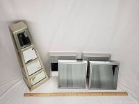 Five silver mirrored wall hangings shown on plain background including one tall column with five mirrored panels and four square frames.