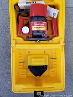 Top view of the router inside the open yellow case showing red router motor with handles, power cord, and manual.