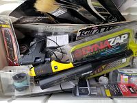 Close-up side angle of the cooler showing the DynaZap insect zapper, glue gun, paintbrushes, and multiple packaged items.