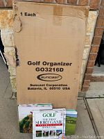 View of original cardboard box for Suncrest Golf Organizer model GO3216D with three golf books standing in front of box