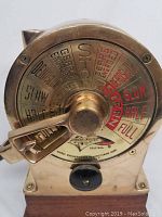 Close-up of brass engine order telegraph dial showing engraved speed commands and brass lever.