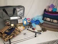 Full sewing lot with machine table, fabrics, scissors, sewing notions and tools displayed together.