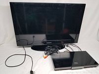 Samsung flat screen TV with cables and Samsung Blu-ray/DVD player on a white surface.