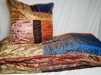 Photo showing the comforter and Euro sham pillow displaying various multi-color fabrics with gold patterning and red bordered edge.