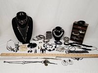 Full view of lot with necklaces on busts, bracelets, rings, and earrings displayed. Ruler for scale included.