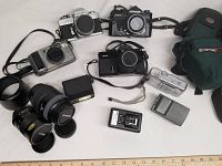 Full view of all cameras, lenses, chargers, flash and carrying cases included in the lot.