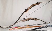 Two takedown recurve bows laid flat alongside the full set of arrows