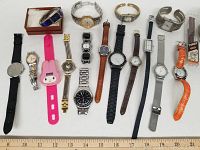 Single image showing 16 watches and watch parts arranged on a white surface with measuring tape