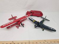 Three metal banks on white background, showing red Shell biplane, dark blue Texaco fighter plane, and red Texaco truck bank with ruler for scale.