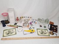 Full view of lot showing assorted items on white cloth including vases, collectibles, trivet tiles, glass pieces, and other small items.