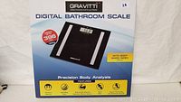 Photo of the packaging showing the Gravitti digital bathroom scale with weight capacity up to 396 pounds and body mass index feature.