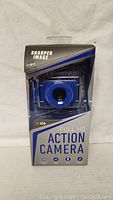 Front view of Sharper Image Full HD Action Camera in retail packaging showing camera lens and branding.