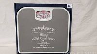 Front view of gray Homebasics bathroom scale with Paris-themed print and analog dial.