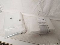 Two folded white PEVA shower curtains or liners, one still in packaging bearing a Mainstays label.