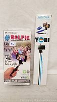 Photo showing two selfie stick boxes: Xtreme #SELFIE universal handheld monopod and Yobi bluetooth remote shutter selfie stick.