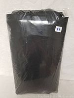 Folded black 60 inch BBQ cover sealed in clear plastic packaging with a white sticker showing number 89.