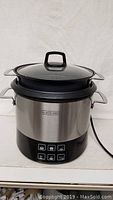 Front view of the Black & Decker rice cooker showing stainless steel body and control buttons.