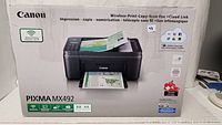 Front view of the Canon Pixma MX-492 printer box showing product image and wireless printing feature.