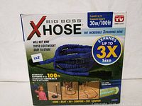 Boxed Big Boss XHose expandable garden hose. Packaging states hose expands up to 3X size, from 30m to 100ft. Blue color hose shown on package.