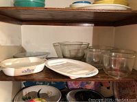 Photo of 2 vintage Corningware platters with blue cornflower design with visible wear and several large heavy glass bowls