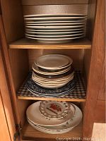 Shelf with stacks of plates and dishes in white, blue patterns, and floral designs