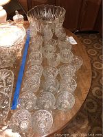 Photo showing two groups of crystal glasses arranged on a table in front of a punch bowl, detailing the cut patterns on cups.
