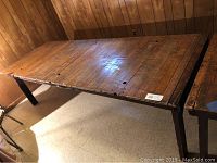 Full view of the rustic solid wood farm table showing rectangular wooden planked top and dark legs