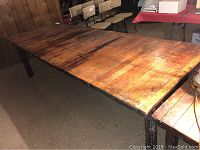 Full view of the farm table showing extensive surface wear, including stains, scratches, and holes.