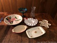 Photo showing all seven pieces on wooden floor including platters, pedestal bowl, vase, chicken-shaped dish, trivet, casserole dish, and rectangular dish.