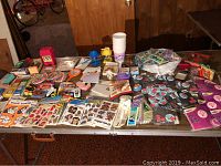 Overview of large assortment of small vintage items spread on a table including stickers, buttons, small toys, and stationery.