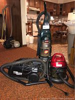 Three vacuum and carpet cleaning units shown: Bissell CleanView carpet cleaner upright, black Eureka MightyMite vacuum canister, red SmartLife vacuum canister.