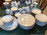 Full set of Towne House Cameo Rose fine china on table showing stacks of plates, bowls, mugs, and serving pieces.