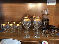 Front view of entire set showing decanter with swivel stopper, 6 wine glasses, 6 small goblets, and 4 Moroccan style cups on shelf