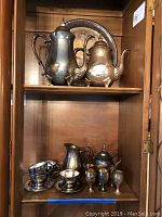 Two coffee urns, creamer, sugar, small goblets, espresso cups and saucers on shelves.