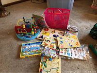 Two colorful wooden bead maze toys with multiple curved wire tracks and beads, along with a collection of over 10 mostly unassembled toddler puzzles in the background, including a Tell-A-Story puzzle box.