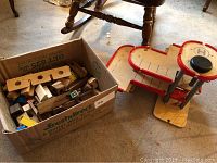 Box of wooden blocks showing multiple blocks in cardboard box and part of parking garage next to it