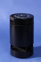 Front view of black cylindrical outdoor speaker with open grill at bottom and solid top.