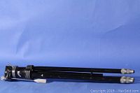 Folded Davidson Star-D Comet tripod laid horizontally on blue background, showing the metal legs with screw-type feet and overall condition with minor paint scratches.