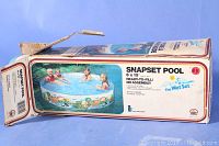Photo of the original packaging box showing the Snapset pool with children playing inside, colorful cartoon design on pool sides visible.